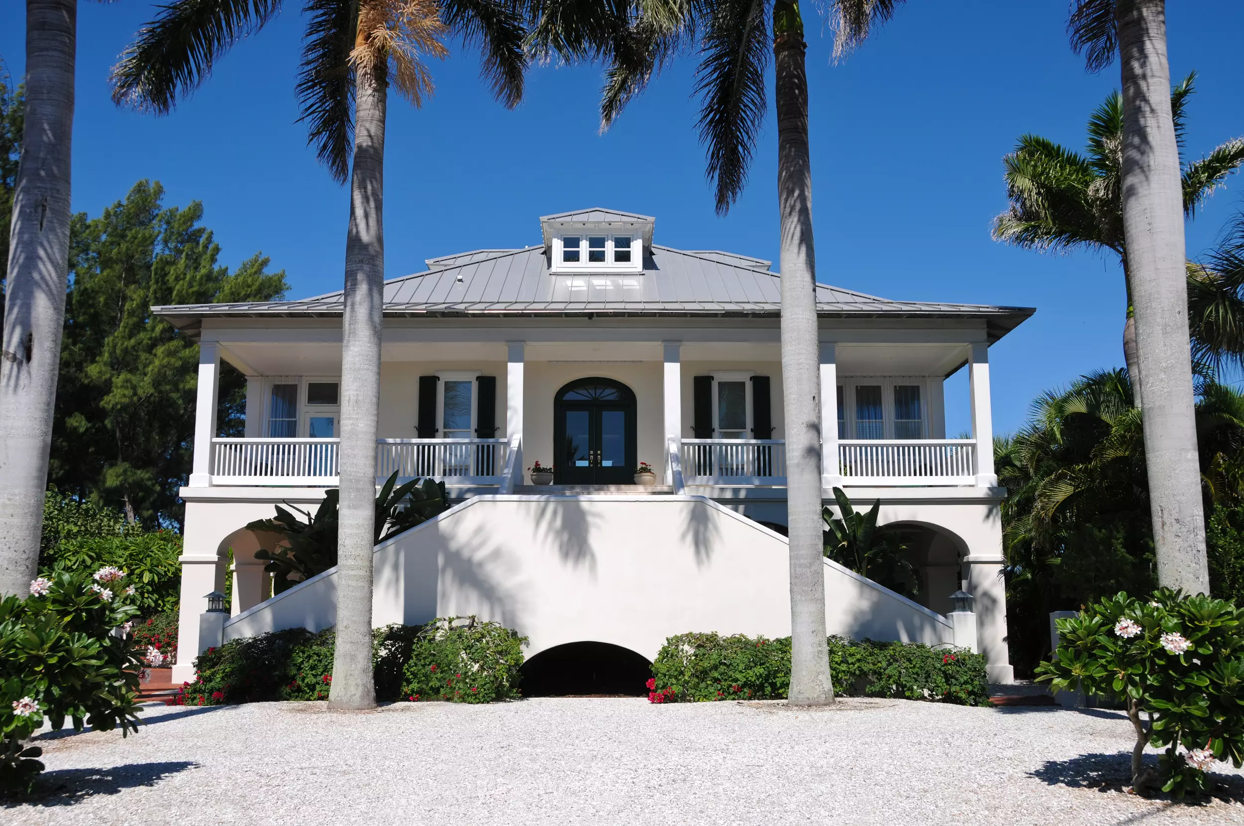 An upscale home with large palm trees in front